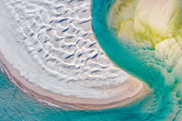 Aerial photograph of the inlet at Peaceful Bay showing turquoise water flowing around a sandy beach and dunes.  Photographed by Christian Fletcher.