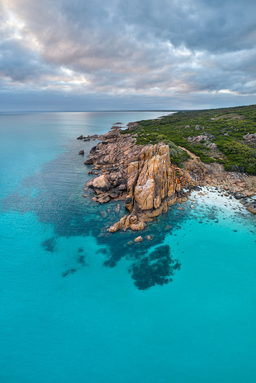 Aerial photograph of Castle Rock, Dunsborough, Western Australia.  The turquoise waters of Geographe Bay with Castle Rock in the foreground looking to Dunsborough in the background.  Morning sunrise with clouds over the calm blue water.